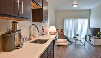 a woman sitting on a couch in an apartment kitchen